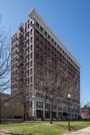 Peoria apartment for rent - a tall brick building with bare trees in front of it