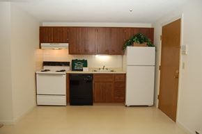 Lowell apartment for rent - an empty kitchen with white appliances and wooden cabinets