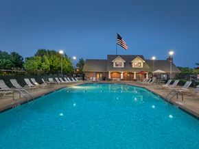 Owasso apartment for rent - a swimming pool with chairs and an flag at night