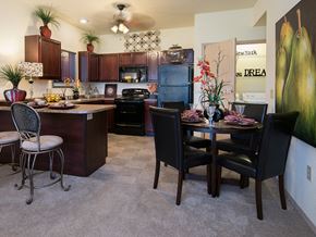 Owasso apartment for rent - a dining room and kitchen with a table and chairs and a refrigerator
