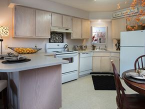 Lowell apartment for rent - a kitchen with white appliances and a table with a bowl of fruit
