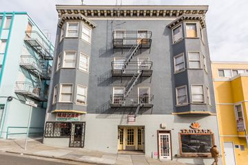 San Francisco apartment for rent - A grey building with a yellow door and windows.