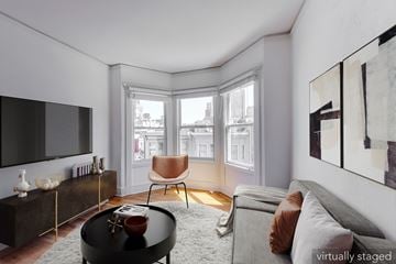 San Francisco apartment for rent - A living room with a grey couch, a black coffee table, a brown chair, a television, and a painting on the wall.