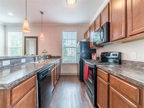 Hilliard townhouse for rent - a kitchen with wooden cabinets and a black refrigerator