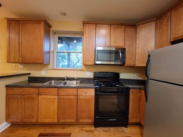 Chicago apartment for rent - a kitchen with wooden cabinets and a black stove and refrigerator
