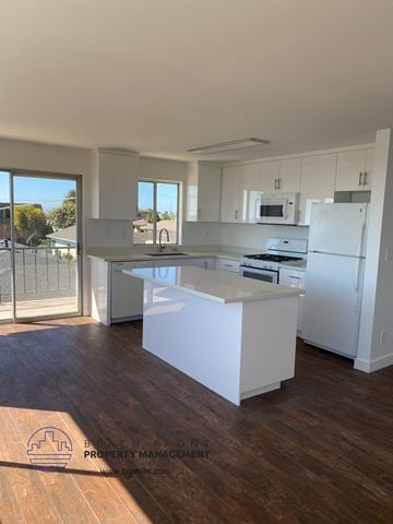 San Pedro apartment for rent - a kitchen with an island and white cabinets and a refrigerator