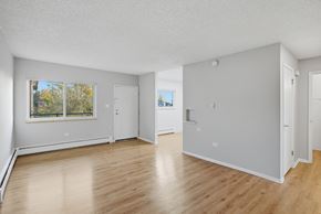 Denver apartment for rent - A spacious room with wooden floors and white walls.