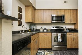 Denver apartment for rent - A kitchen with wooden cabinets and a black stove top oven.