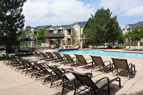 Denver apartment for rent - A row of sun loungers are arranged on a concrete surface in front of a swimming pool.