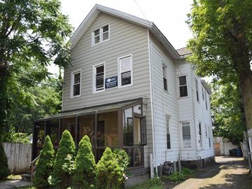 New Haven apartment for rent - A house with a grey facade surrounded by green trees.
