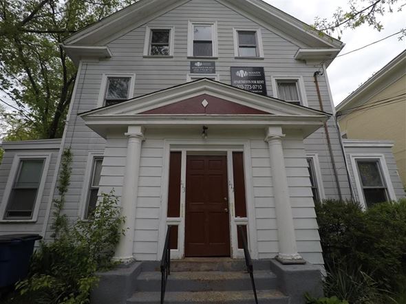 New Haven apartment for rent - A white house with a brown door and a sign above it.