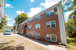New Haven apartment for rent - A red brick building with white trim and a car parked in front.