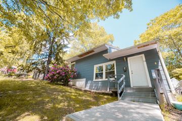New Haven apartment for rent - A small house with a white door and windows surrounded by trees.