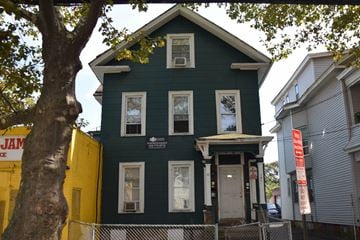 New Haven apartment for rent - A green house with a yellow building behind it.