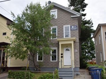 New Haven apartment for rent - A grey house with a white door and a tree in front.