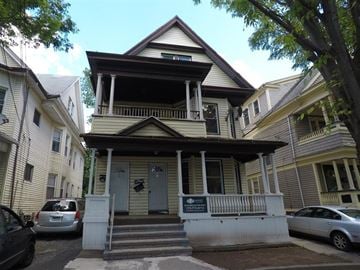 New Haven apartment for rent - A two-story house with a porch and a sign on the front door.