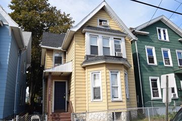 New Haven apartment for rent - A yellow house with a black door and a window is in front of a green house.