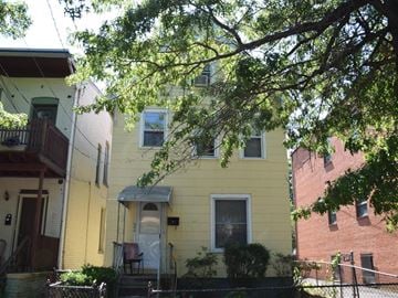 New Haven apartment for rent - A yellow house with a tree in front.