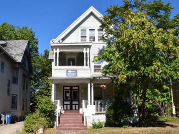 New Haven apartment for rent - A white two-story house with a blue sign on the front door.
