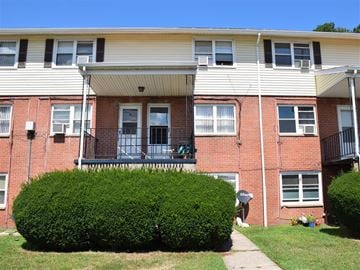 New Haven apartment for rent - A red brick building with a green bush in front.