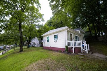 New Haven apartment for rent - A small house with a porch is surrounded by trees.