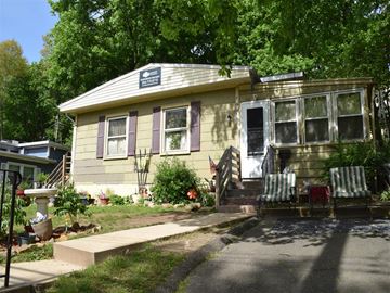 New Haven apartment for rent - A yellow house with a porch and a sign on the roof.