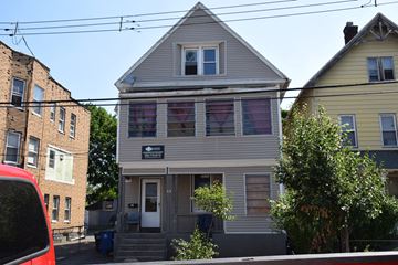 New Haven apartment for rent - A grey house with a red car parked in front.