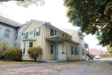 New Haven apartment for rent - A yellow house with green shutters and a grey door.