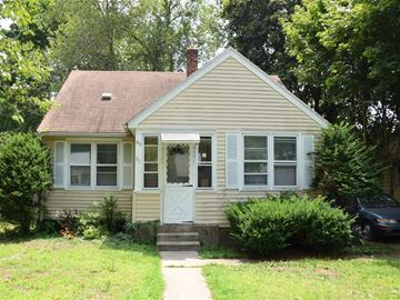 New Haven apartment for rent - A small house with a white door and windows surrounded by greenery.
