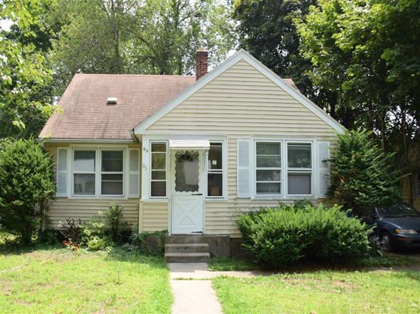 New Haven apartment for rent - A small house with a white door and windows surrounded by greenery.