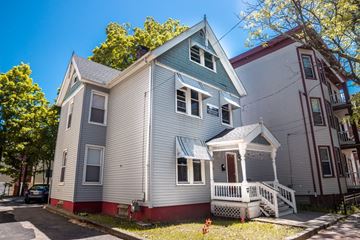 New Haven apartment for rent - A house with a blue roof and white siding is surrounded by trees.