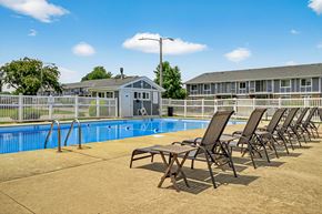 Kenosha apartment for rent - A pool with chairs around it and a building in the background.