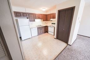 Ames apartment for rent - an empty kitchen with white appliances and wooden cabinets