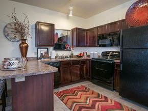 Grandview apartment for rent - a kitchen with black appliances and wooden cabinets and a rug