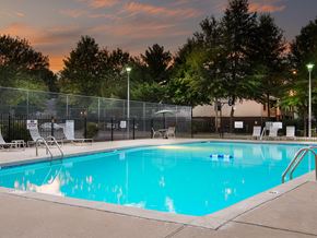 Rogers apartment for rent - a swimming pool at dusk with chairs and a fence around it