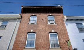 Manayunk triplex for rent - A red brick building with three windows.