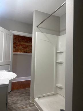 Manayunk triplex for rent - A white bathroom with a brick wall in the background.