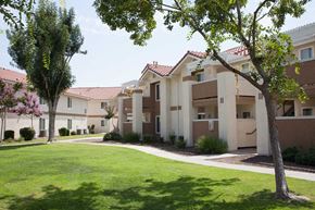 Fresno apartment for rent - a building with a green lawn and trees in front of it