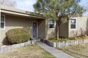Albuquerque apartment for rent - a brown house with a tree and a sidewalk