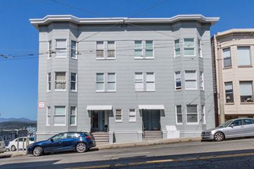 San Francisco apartment for rent - A grey building with a blue car parked in front.