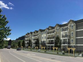 Kelowna apartment for rent - A row of apartment buildings with a car driving by on the street.