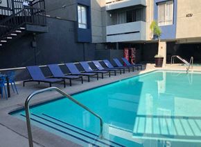 North Hollywood apartment for rent - a swimming pool with blue chairs next to a building