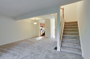 Amherst townhouse for rent - an empty living room with stairs and a kitchen in the background