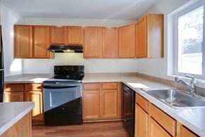Amherst townhouse for rent - an empty kitchen with wooden cabinets and black appliances
