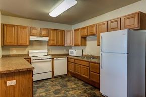 Tioga apartment for rent - a kitchen with white appliances and wooden cabinets