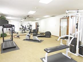 Fayetteville apartment for rent - a gym with cardio equipment and weights on the floor