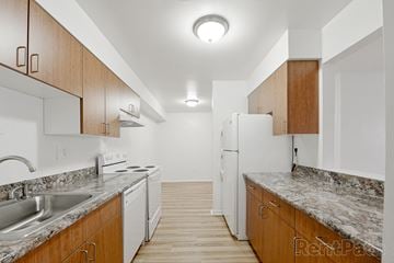 Merrillville apartment for rent - a kitchen with marble counter tops and white appliances and wooden cabinets