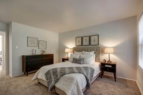 St. Louis townhouse for rent - Georgetown Apartments of St. Louis bedroom with tufted headboard, nightstands, lamps, dresser and textured throw.