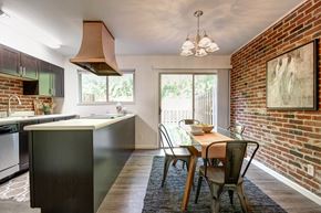 St. Louis townhouse for rent - Dining area and open kitchen with exposed brick wall and sliding glass door at Georgetown Apartments of St. Louis.