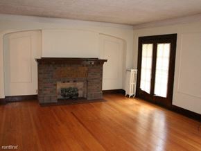 Rockford apartment for rent - an empty living room with a brick fireplace and wooden floors
